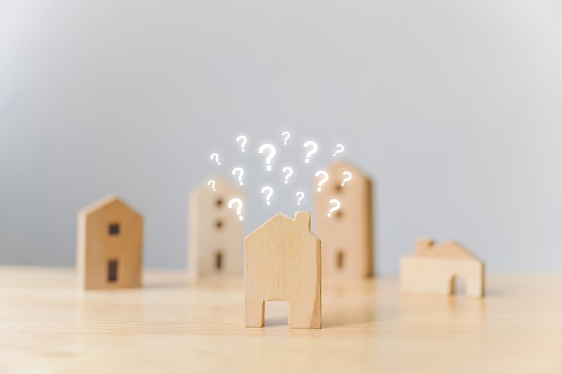 Real estate developer and managing property investment concept. Selective focus wooden houses with question mark on wood table